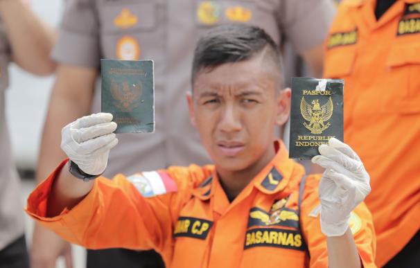 Un rescatista muestra los pasaportes de dos pasajeros del accidente aéreo de este lunes en el puerto de Tanjung Priok