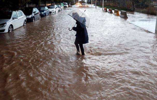 Una persona cruza una calle inundada durante la tarde de hoy en la que el temporal de lluvia torrencial ha azotado por tercera jornada consecutiva la provincia de Valencia.