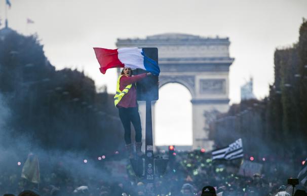 Una joven con el chaleco amarillo ondea una bandera francesa durante la protesta en los Campos Elíseos de París (EFE/EPA/CHRISTOPHE PETIT TESSON)