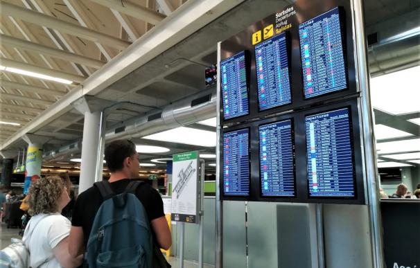 Dos viajeros consultan la información de vuelos en las pantallas del aeropuerto