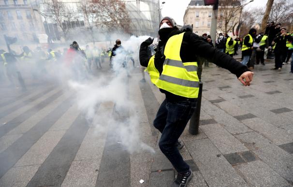 Un manifestante de los chalecos amarillos lanza un objeto a las fuerzas policiales durante una manifestación cerca de los Campos Elíseos en París, Francia, el 8 de diciembre de 2018. (EFE/EPA/IAN LANGSDON)