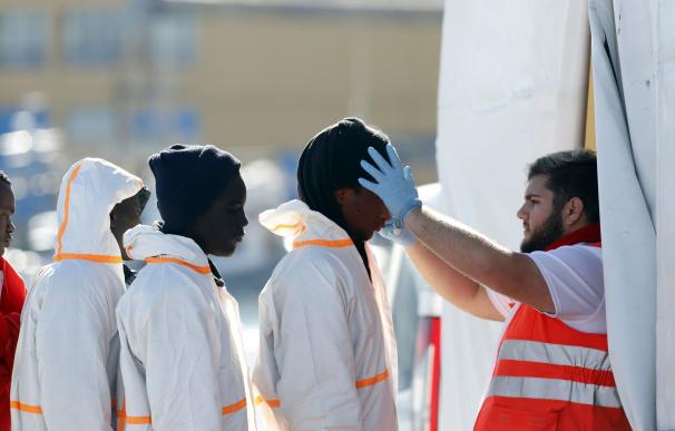 Un miembro de Cruz Roja atiende a inmigrantes llegados al puerto de Málaga