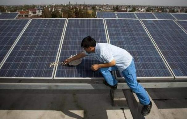 Un trabajador limpia una placa solar en la azotea de un edificio. EFE