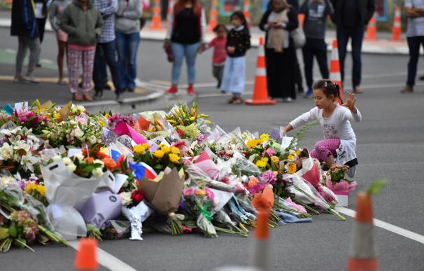 Una niña coloca flores en un monumento improvisado en Christchurch, Nueva Zelanda, el 16 de marzo de 2019 (EFE/EPA/MICK TSIKAS)