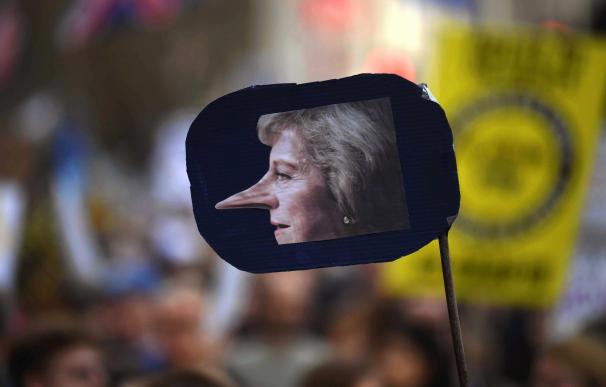 Un cartel que muestra una foto de la primera ministra británica, Theresa May, con la nariz de Pinocho, durante la marcha para exigir otro referéndum del Brexit (EFE/EPA/NEIL HALL)