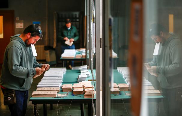 Ciudadanos buscan su papeleta de voto en un colegio de Barcelona. EFE/Enric Fontcuberta