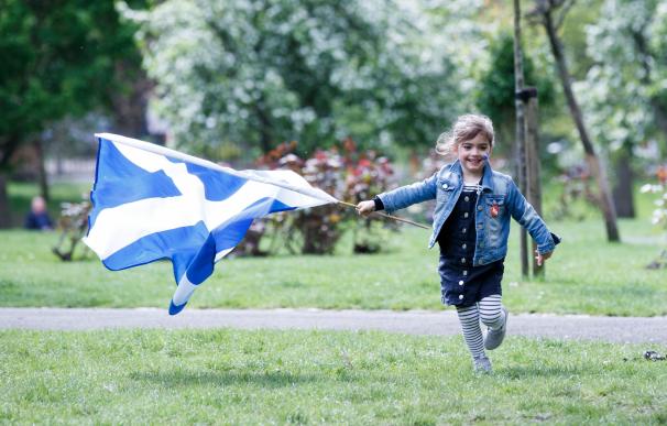 Una niña corre con una bandera escocesa mientras asisten a la marcha de All Under One Banner (AUOB) en Glasgow, Escocia. /EFE