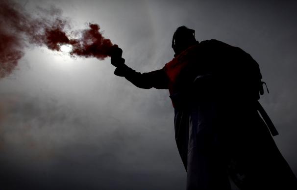 Un trabajador de Alcoa con un bote de humo en la cabecera de la manifestación de A Coruña. /EFE/Cabalar