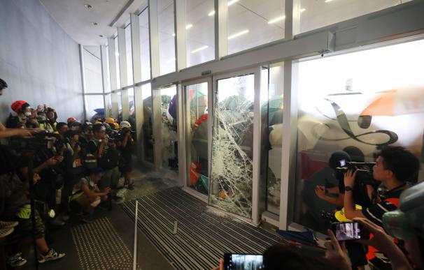 Varios periodistas aguardan tras las puertas acristaladas mientras varios manifestantes intentan irrumpir en el Consejo Legislativo en Hong Kong (China)
