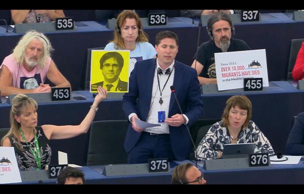 El eurodiputado irlandés Matt Carthy interviene reivindicando a Puigdemont mientras Martina Anderson sujeta un cartel con su cara.