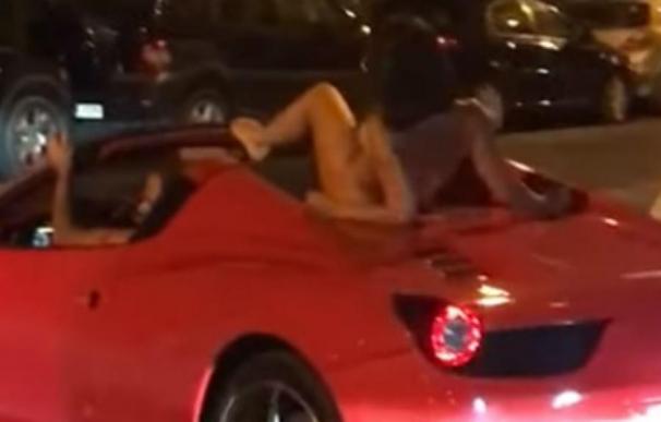 Un hombre conduce su ferrari con una mujer sobre el coche por Ibiza