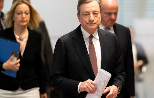Draghi camina hacia la rueda de prensa escoltado por Guindos.