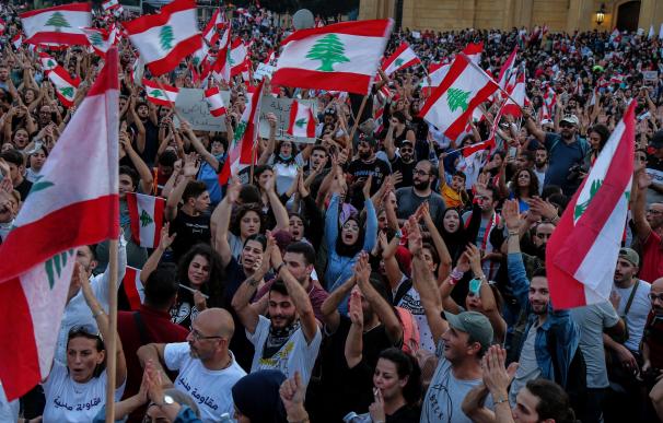 Los manifestantes agitan banderas libanesas y gritan consignas antigubernamentales durante una protesta frente al palacio de gobierno en el centro de Beirut. /EFE