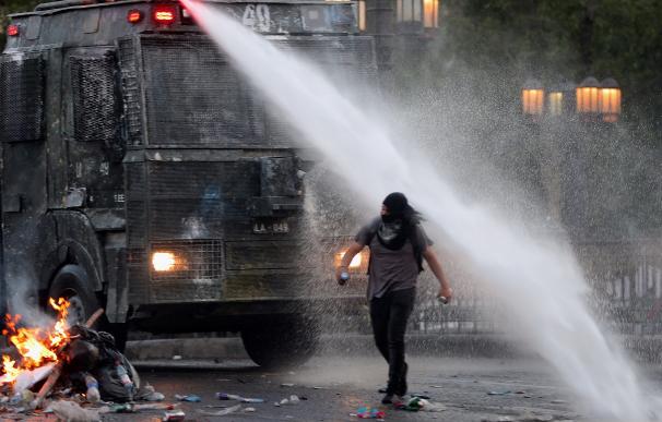 Un manifestante camina bajo el chorro de agua lanzado por la policía durante una nueva jornada de protestas. /EFE