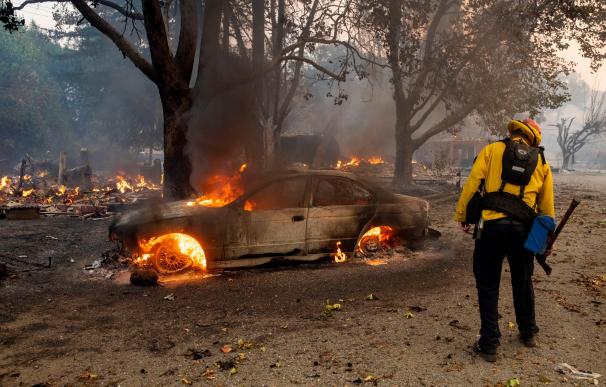 Un bombero echa un vistazo a un coche en llamas mientras el incendio de Kincade arde en las colinas sobre Geyserville, California. /EFE/EPA/PETER DASILVA