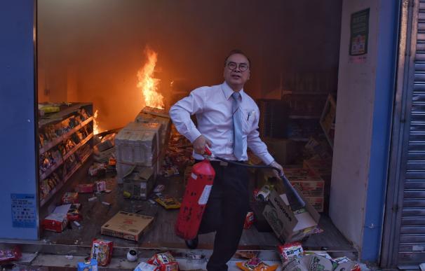 Un hombre con un extintor de incendios camina junto a una tienda destrozada durante el mitin a favor de la democracia en Hong Kong. /EFE/EPA/MIGUEL CANDELA