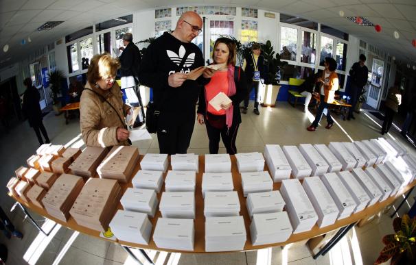 Los primeros votantes del colegio público Pinar del Rey de Madrid recogen papeletas electorales para ejercer su derecho al voto. /EFE/Javier Lizón