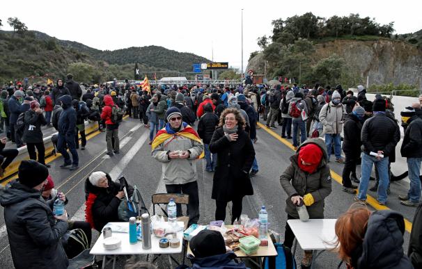 Varios manifestantes se avituallan durante el bloqueo de la autopista que enlaza España y Francia en el paso de La Jonquera. /EFE/Alejandro Garcia