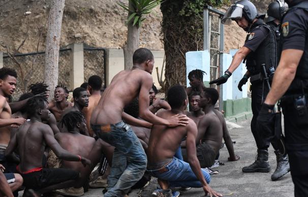 Imagen de inmigrantes y efectivos policiales ante el salto masivo a la valla de Ceuta el 30 de agosto