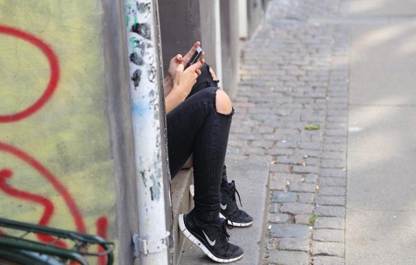 Fotografía de una niña adolescente con su móvil.