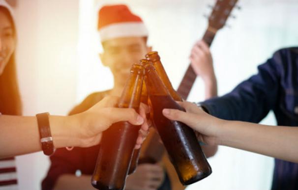Grupo de amigos celebra la navidad compartiendo unas cervezas.