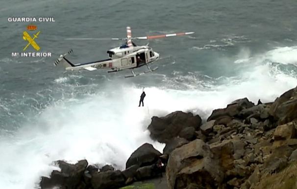 Un guardia civil protege de las envestidas del mar a un pescador con una pierna rota que cayó a un acantilado
