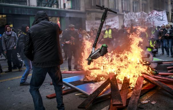Manifestantes y 'chalecos amarillos' arrojan patinetes a una barricada en llamas durante una manifestación contra las reformas de pensiones. /EFE/EPA