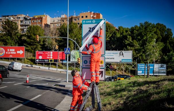 Operarios instalando las señales de tráfico definitivas de la ZBE Rondas BCN en el ramal de la salida 14 Besòs de la Ronda de Dalt, en L'Hospitalet de Llobregat