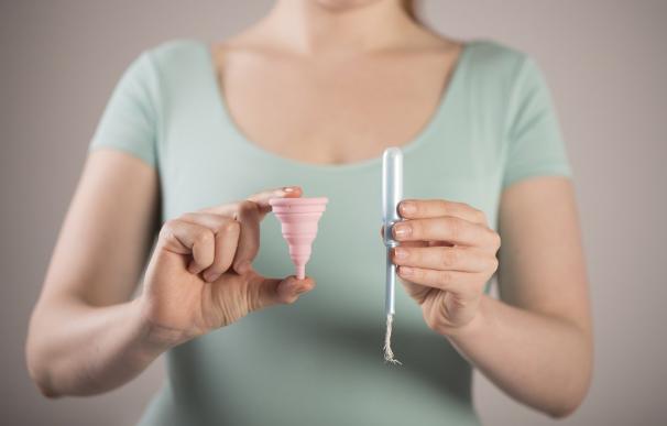 Fotografía de una copa menstrual y de un tampón.