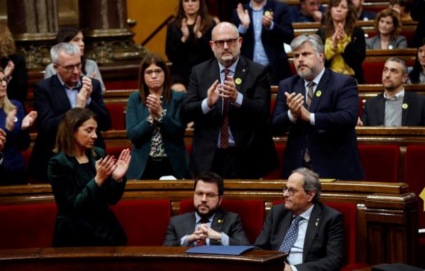 El presidente de la Generalitat, Quim Torra (d), es aplaudido por los miembros de su partido mientras que su vicepresidente, Pere Aragonés (i), y los diputados de ERC permanecen sentados. /EFE