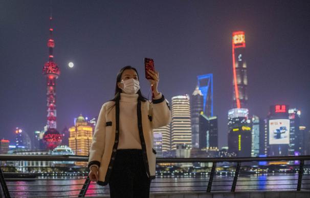 Una mujer con máscara se saca una foto en Shangái.