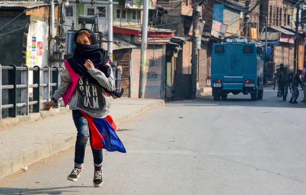 Una mujer pasa ante una patrulla policial en la Cachemira india