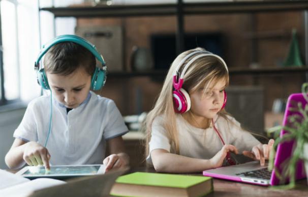 Dos niños realizan las tareas del colegio en su ordenador