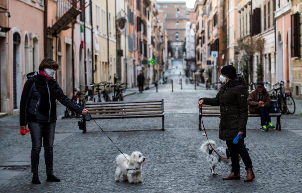 Fotografía de dos personas paseando al perro en Roma durante la crisis del coronavirus.