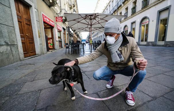 Un hombre con una máscara para protegerse contra el COVID-19 pasea a su perro en Turín, Italia, el 26 de febrero de 2020. /EFE / EPA / Tino Romano