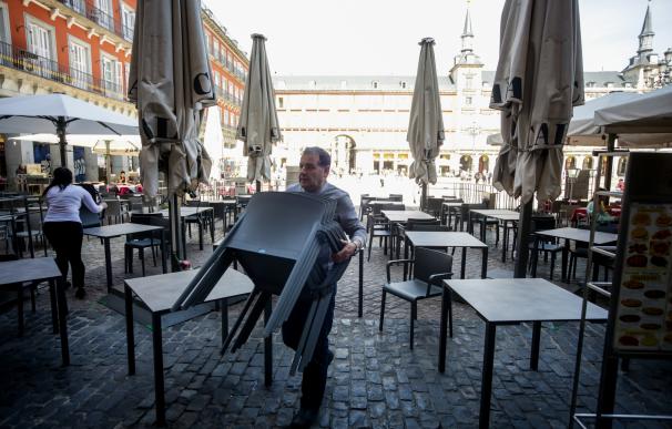 Varios empleados de un bar de la Plaza Mayor de Madrid recogen la terraza un día antes de que se cierre toda la hostelería para frenar contagios por coronavirus, en Madrid