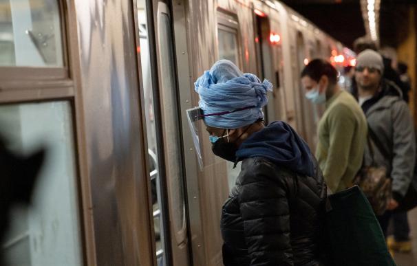Una mujer con mascarilla y pantalla protectora en el metro de Nueva York