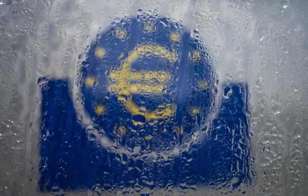 FILED - 19 March 2020, Hessen, Frankfurt_Main: Water droplets slide down the glass covering the euro symbol at the south entrance to the headquarters of the European Central Bank (ECB). The global economy will contract 3 per cent this year due to the new
