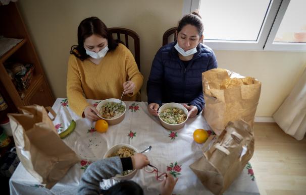 Dos mujeres y un niño en su casa en Carabanchel con el menú de la ONG del chef José Andrés, que reparte a las familias más necesitadas