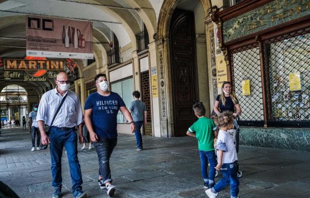 Personas con mascarillas caminan bajo las arcadas de la Piazza San Carlo durante la fase 2 de la emergencia del coronavirus, en Turín, Italia. /EFE