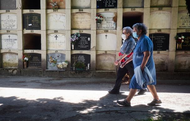 Dos personas protegidas con mascarillas acuden a visitar a sus familiares en el cementerio