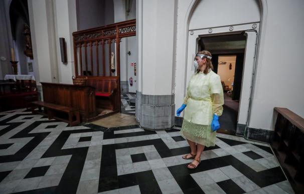 Una enfermera camina en una iglesia con equipo de protección para administrar la prueba de detección Covid-19 en una iglesia en Amberes, Bélgica