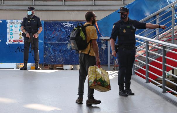 Un agente de la Policía Nacional da indicaciones a un pasajero mientras vigilan la Estación de Atocha Renfe, en Madrid
