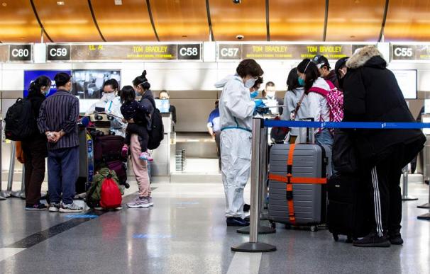 Empleados revisan la temperatura de los pasajeros en el Aeropuerto Internacional LAX en Los Ángeles, California