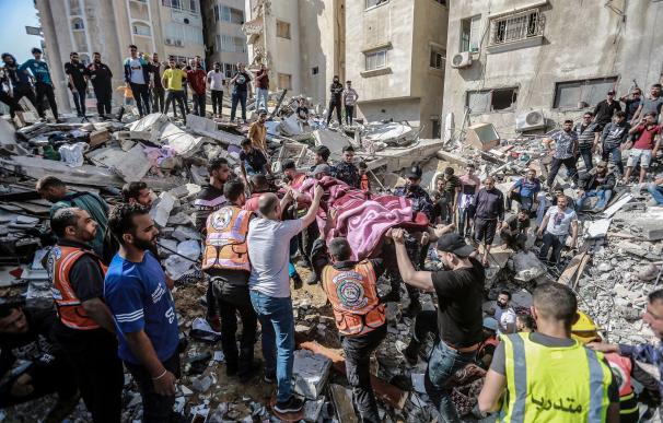 Paramédicos palestinos desentierran el cuerpo de una persona en una casa colapsada por un ataque de las fuerzas israelíes.