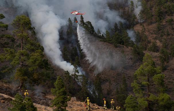 Un helicóptero del Gobierno de Canarias descarga agua sobre una de las zonas del incendio en el municipio de Arico, tenerife.