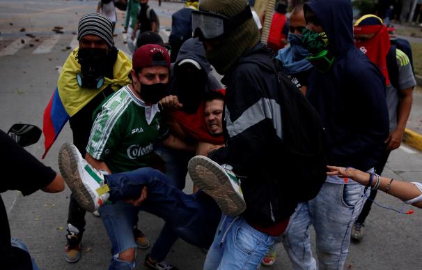 Manifestantes cargan un herido presuntamente por disparo de arma de fuego durante enfrentamientos con la policía en Cali, Colombia.