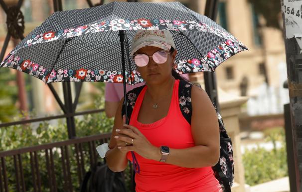 Una mujer se protege del sol con un paraguas durante un día de alerta roja por altas temperaturas en la ciudad de Murcia.