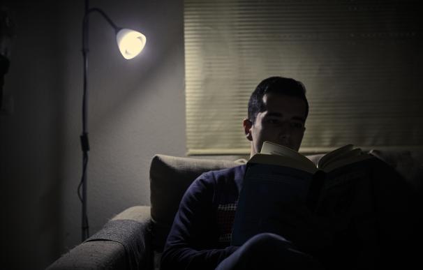 Un chico lee un libro bajo la luz