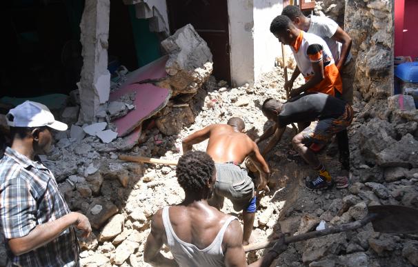 Un grupo de personas en Puerto Príncipe remueve escombros tras el terremoto que afectó a Haití el sábado.